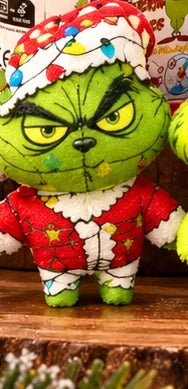 Green grumpy holiday character wearing a brightly decorated festive hat